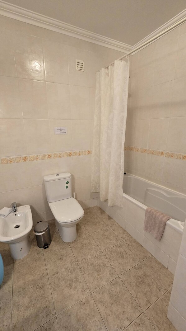 A bathroom with a toilet, bidet, sink, and bathtub.