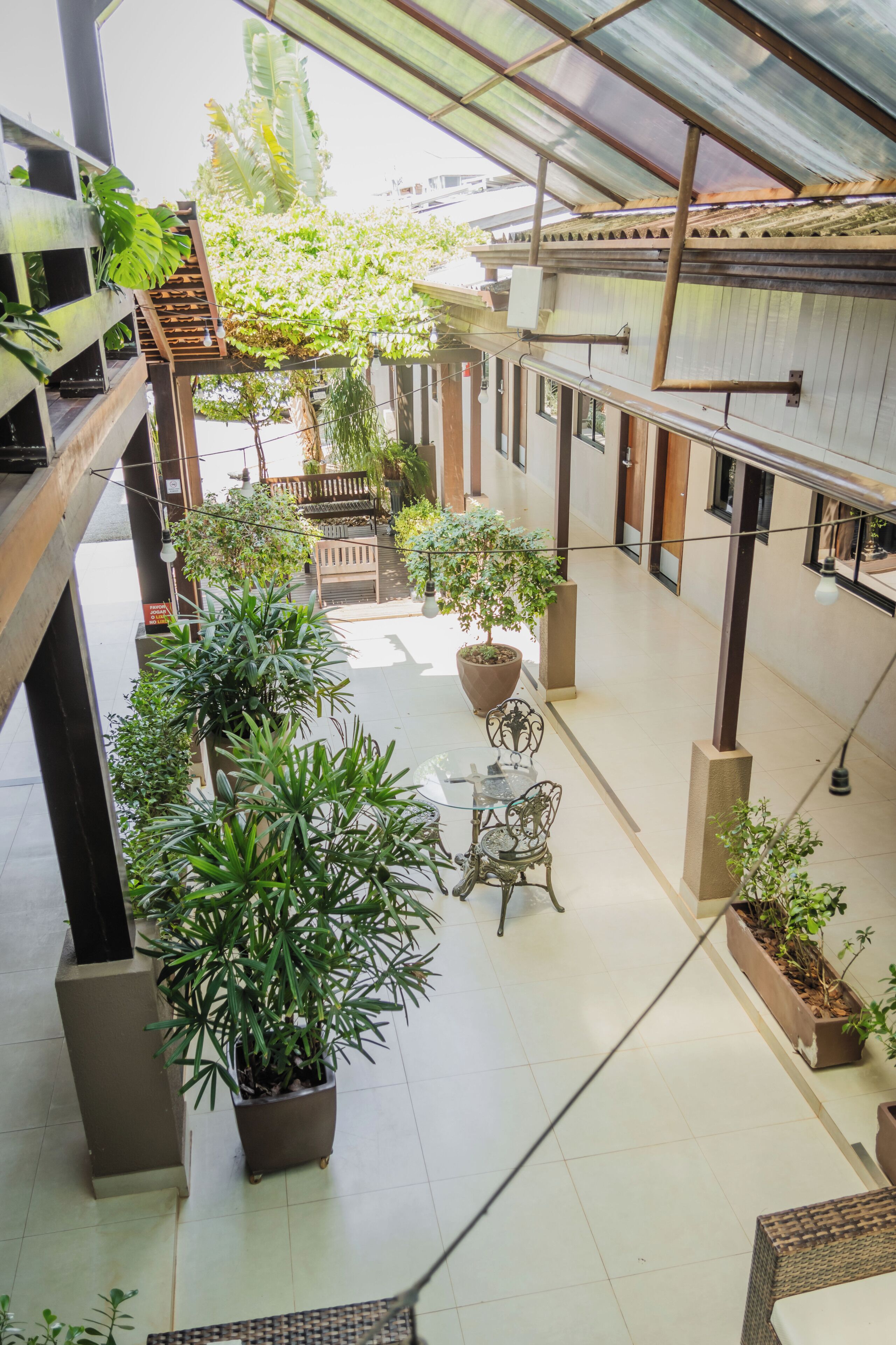 An indoor courtyard with potted plants, a wooden bench, and a glass table.