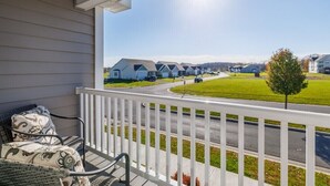 A balcony with wicker furniture and a view of a row of houses and a road. - Relax in Style, Golf course Community Townhouse - 3440 (Baldwinsville)