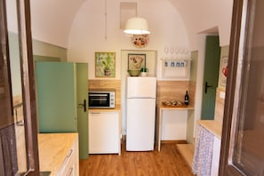 A compact kitchen with a microwave, toaster, and refrigerator. There are decorative items and a wine rack on the wall.