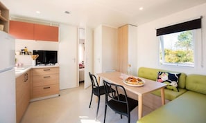 Une cuisine compacte avec une table et des chaises, un canapé vert et une fenêtre donnant sur un beau paysage.