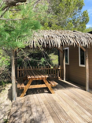 A wooden deck with a picnic table and a thatched-roof structure.