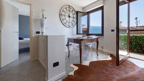 Una habitación moderna con un ventanal grande, un reloj de pared redondo, una mesa de madera y un tapete de cuero de vaca.