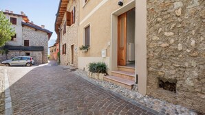 Una estrecha calle adoquinada flanqueada por edificios de piedra con puertas y ventanas de madera.