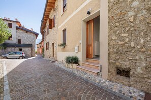A narrow cobblestone street flanked by stone buildings with wooden doors and windows.