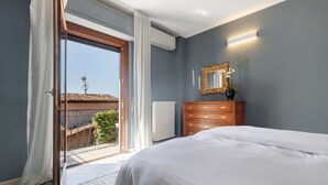 Un dormitorio con cama, cómoda, espejo y puerta corrediza de vidrio que da a un balcón.