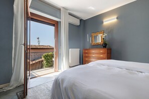 A bedroom with a bed, a dresser, a mirror, and a sliding glass door leading to a balcony.