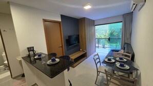 Un espacio habitable compacto con kitchenette, comedor y televisor montado en la pared.