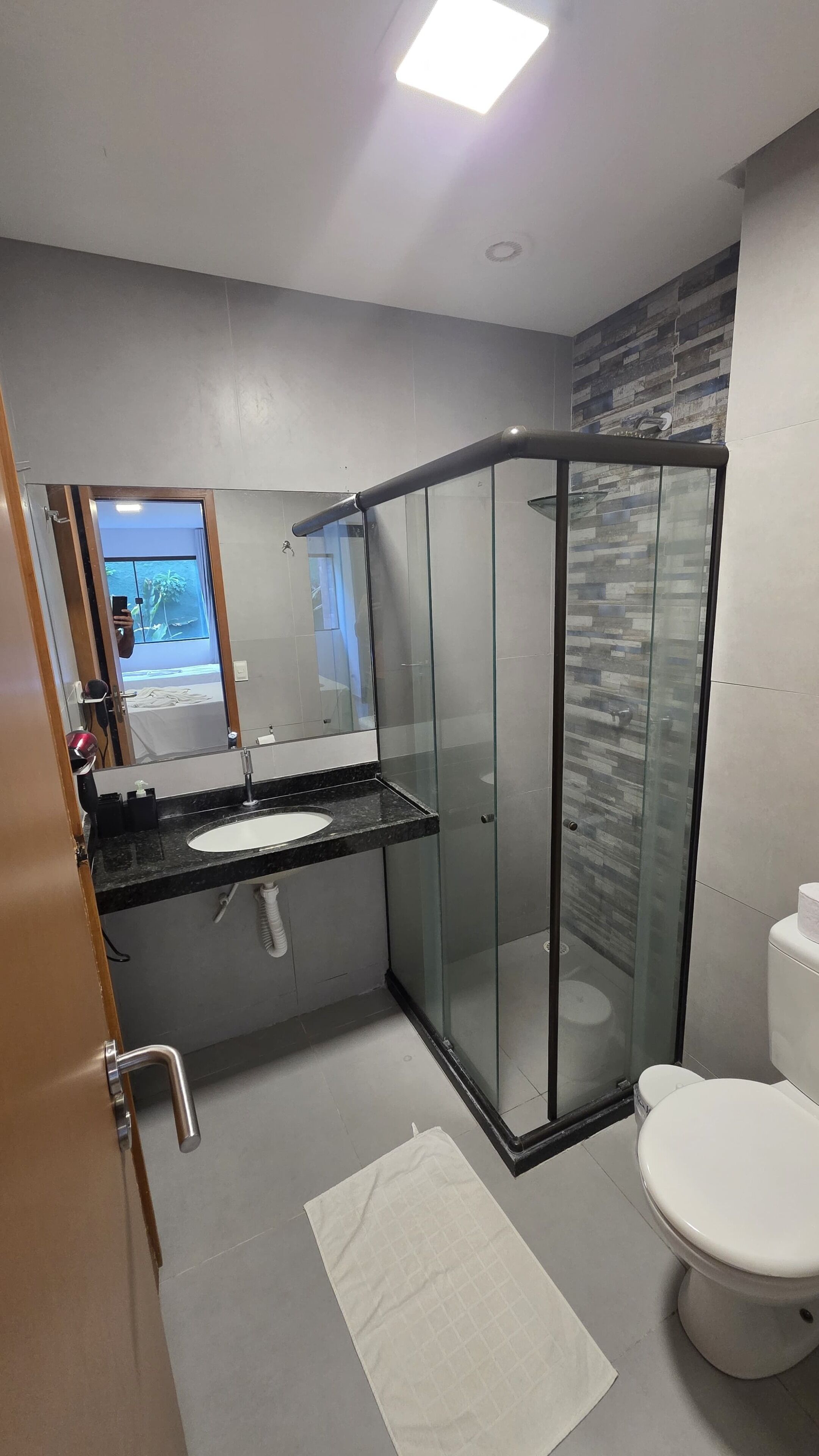 Un baño moderno con cabina de ducha de vidrio, un lavamanos con espejo y un inodoro.