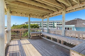A wooden deck with benches, a railing, and a view of buildings in the background.