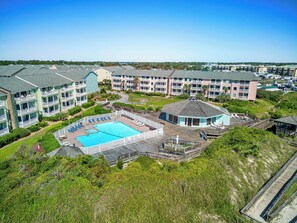 A multi-story hotel with a swimming pool, outdoor deck, and a view of the surrounding landscape.