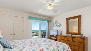 A bedroom with a bed, a dresser, a television, and a balcony with a view. - Almost Oceanfront 3 Bedroom Pebble Beach C-304 Condo (Emerald Isle)