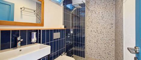 A bathroom with a white sink, a toilet, a shower with a glass door, and a mirror above the sink.