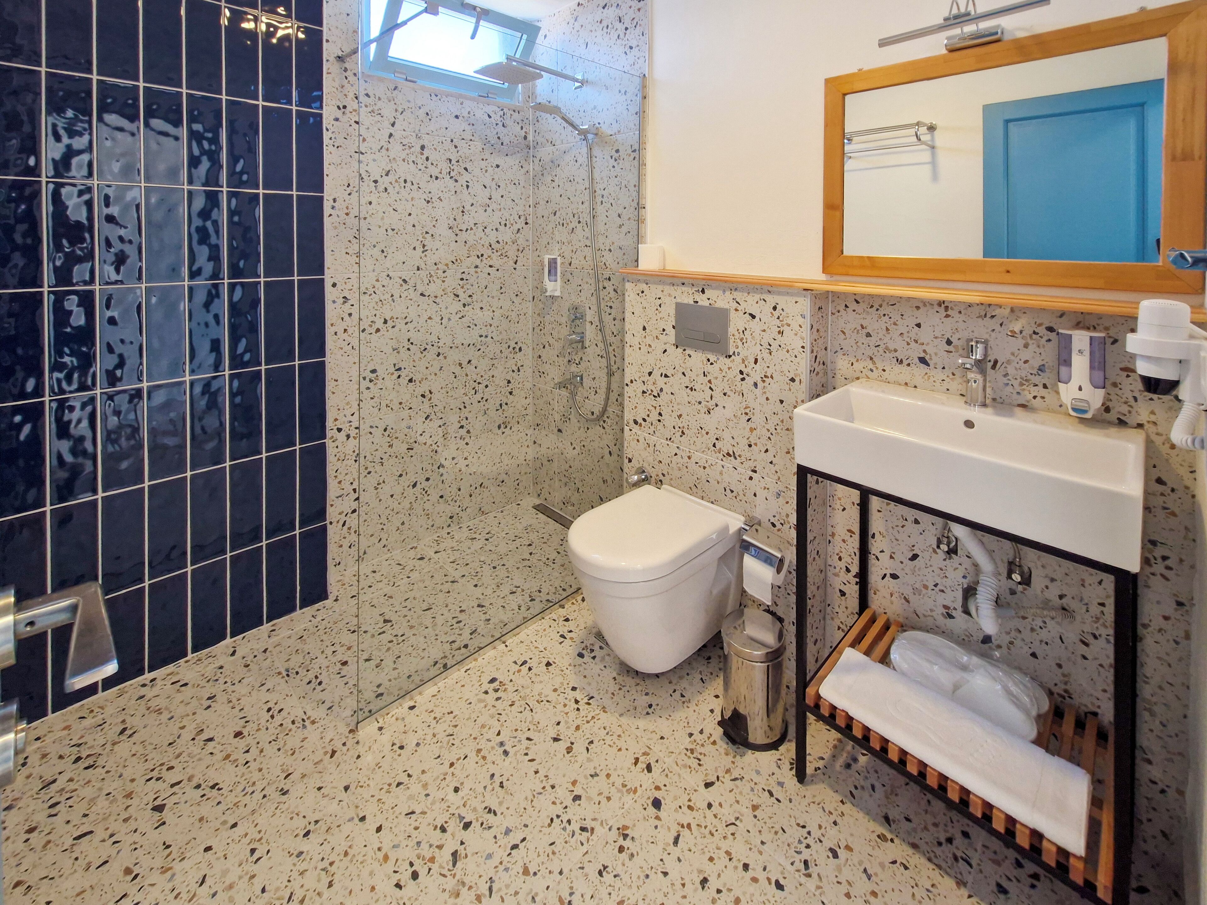 A bathroom with a shower, toilet, sink, and a mirror above the sink.