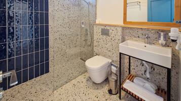 Un baño con ducha, inodoro, lavamanos y un espejo sobre el lavamanos.