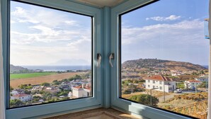 Une chambre d’angle dotée de deux grandes fenêtres donnant sur une ville côtière et des collines.