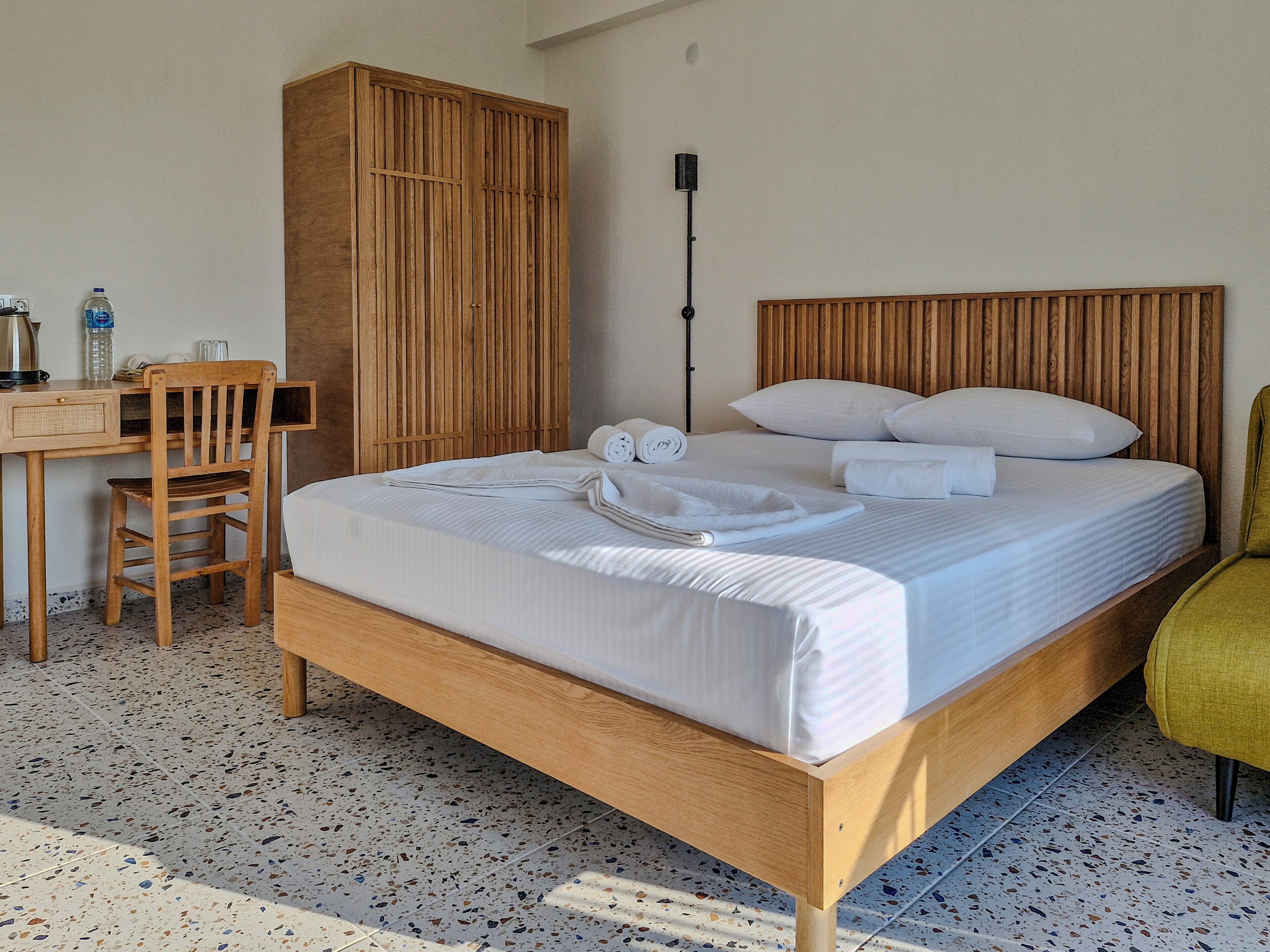 A neatly arranged hotel room with a wooden bed, a desk, and a chair.