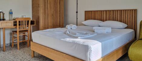 A neatly arranged hotel room with a wooden bed, a desk, and a chair.
