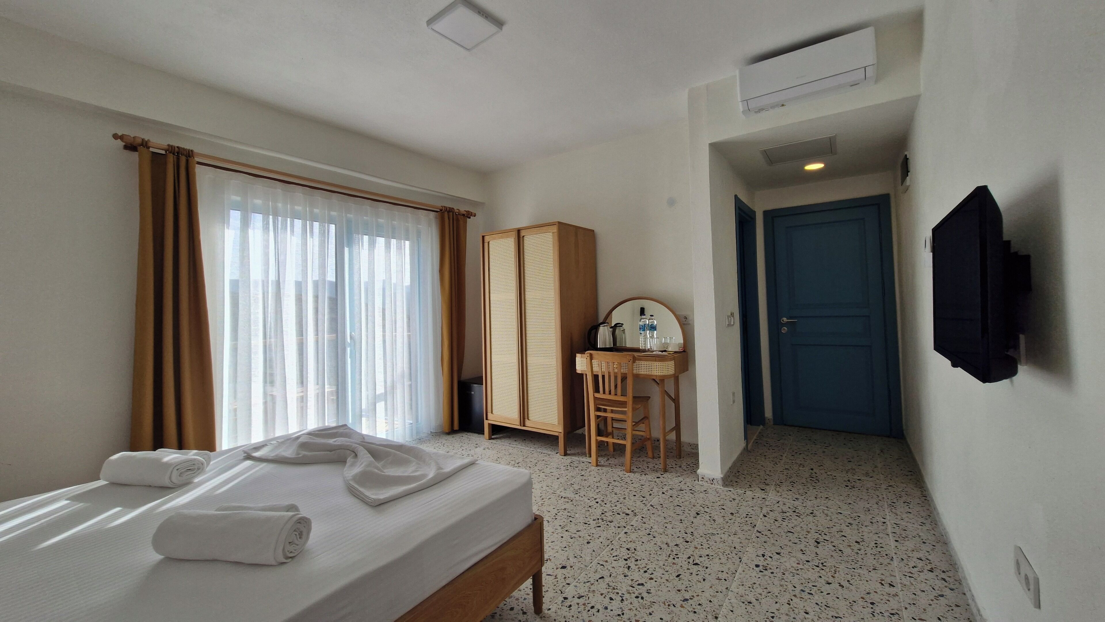 Hotellihuone, jossa on sänky, työpöytä tuolilla, vaatekaappi ja ovi.