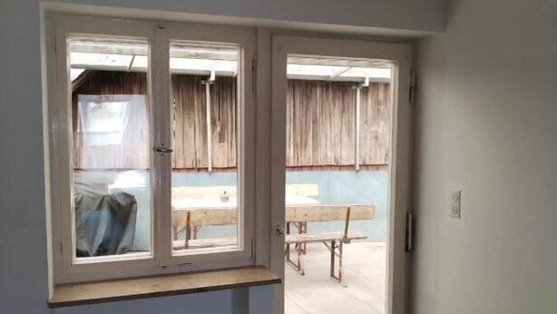 A room with a sliding glass door leading to an outdoor patio area. - Landarbeiterhaus (Moettingen)