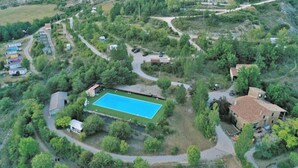 Une vue aérienne d’un quartier résidentiel avec une piscine entourée de verdure, quelques maisons et des routes sinueuses.
