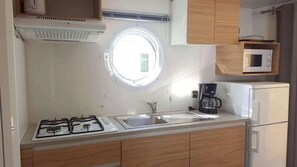 A compact kitchen with a gas stove, a sink, a coffee maker, and a microwave.