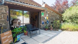 Une boutique à la façade en pierre, dotée d’une porte d’entrée en verre et d’un espace extérieur aménagé pour les clients.