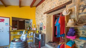 Un intérieur rustique avec un mur en pierre, un tonneau en bois et des étagères remplies de divers objets.