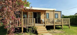 A single-story wooden cabin with a porch, a small outdoor seating area, and a visible door. - ZEcamping 3 étoiles animaux acceptés sauna piscine couverte (Mont-prés-Chambord)