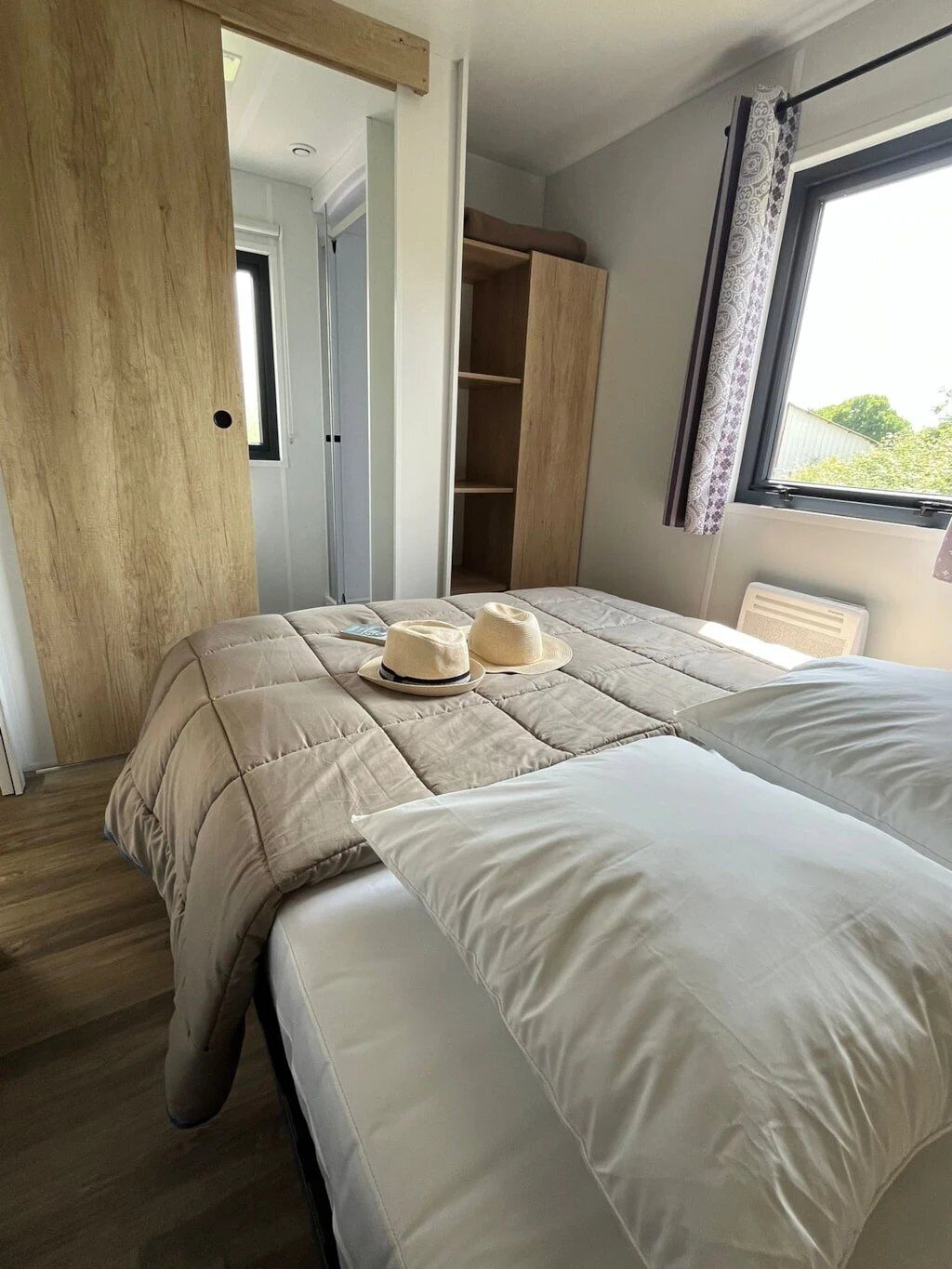 Une chambre à coucher avec un grand lit, une armoire et une fenêtre avec des rideaux.