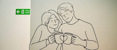 Dibujo de dos personas sosteniendo tazas, con un letrero de salida de emergencia al fondo.