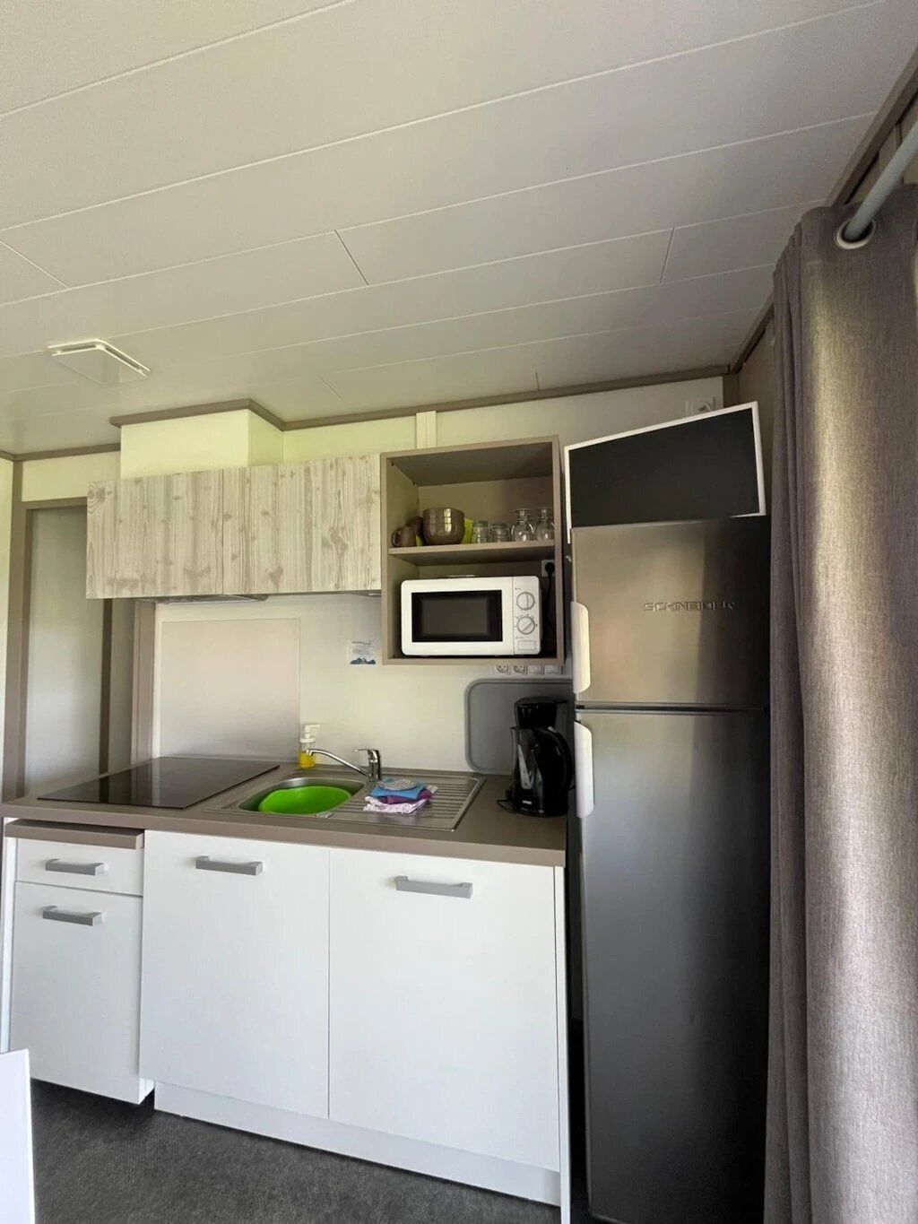 Una cocina compacta con microondas, cafetera y lavabo.