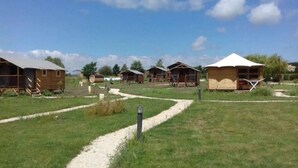 Un camping con varias cabañas de madera, un camino de grava y cielo despejado.