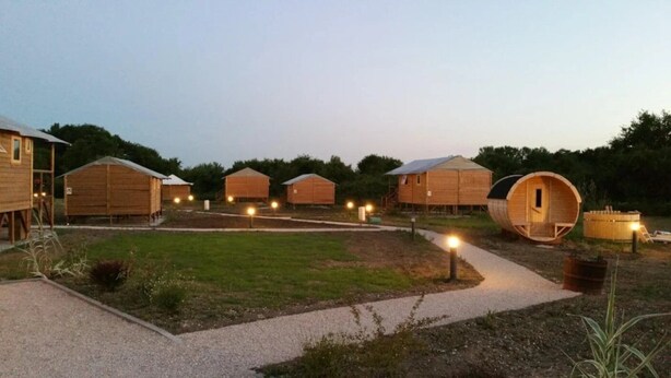 A row of wooden cabins with a gravel path in the foreground.