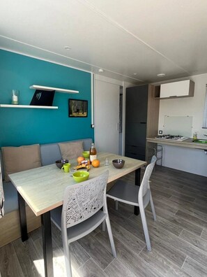 Une cuisine moderne dotée d’une cuisinière intégrée et d’un coin repas avec une table et des chaises.