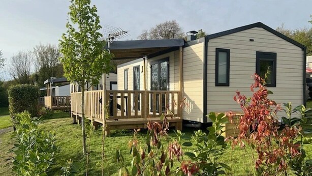 A mobile home with a deck, surrounded by greenery and a clear sky. - ZEcamping 3 étoiles chiens acceptés animations piscine chauffée (Grand-Laviers)