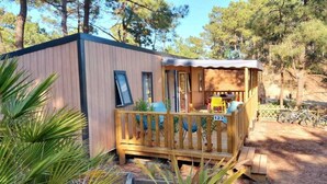 Eine kleine Holzhütte mit einer Terrasse, nummeriert 123, umgeben von Bäumen.
