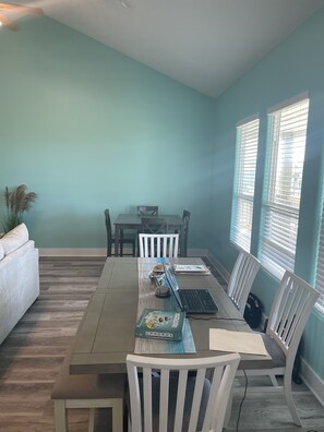 Enjoy meals in this cozy dining area with a long table for four, white chairs, and a comfortable sofa.