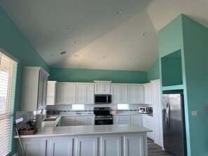 Kitchen features stainless steel appliances, a central island, and a window with blinds.