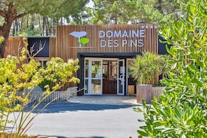 A building with a sign reading "DOMAINE DES PINS". - ZEcamping 4* piscine couverte 2km plage animations locatif TV LV 40m2 (Saint-Hilaire-de-Riez)