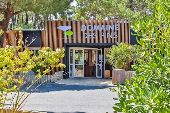Un bâtiment sur lequel on peut lire l’inscription « DOMAINE DES PINS » et qui arbore un logo représentant un arbre avec une feuille.