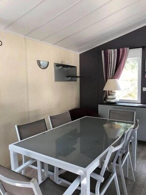 A dining area with a glass-top table and white chairs.