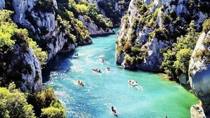 Um rio rodeado por penhascos, com barcos e pessoas.