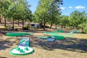 An outdoor play area with green structures and trees in the background.