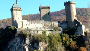 A medieval castle with three prominent towers, situated on a rocky hill with autumn foliage. - ZEcamping 4* familial piscine dog friendly locatif TV BBQ 35m2 7 pers (La Bastide-de-Sérou)