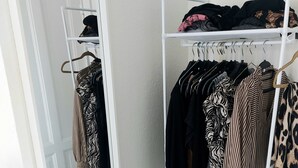 Habitación con un armario blanco, un espejo y un zapatero. Hay mancuernas negras en el suelo.