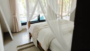 A bedroom with a bed, white curtains, and a view of the outdoors. - Saga Villas Oasis - Stylish 2BR villa in excellent location (Bali)