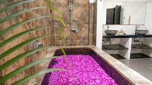 A bathroom with a large bathtub filled with pink flowers, a shower, and a sink area. - Saga Villas Oasis - Stylish 2BR villa in excellent location (Bali)