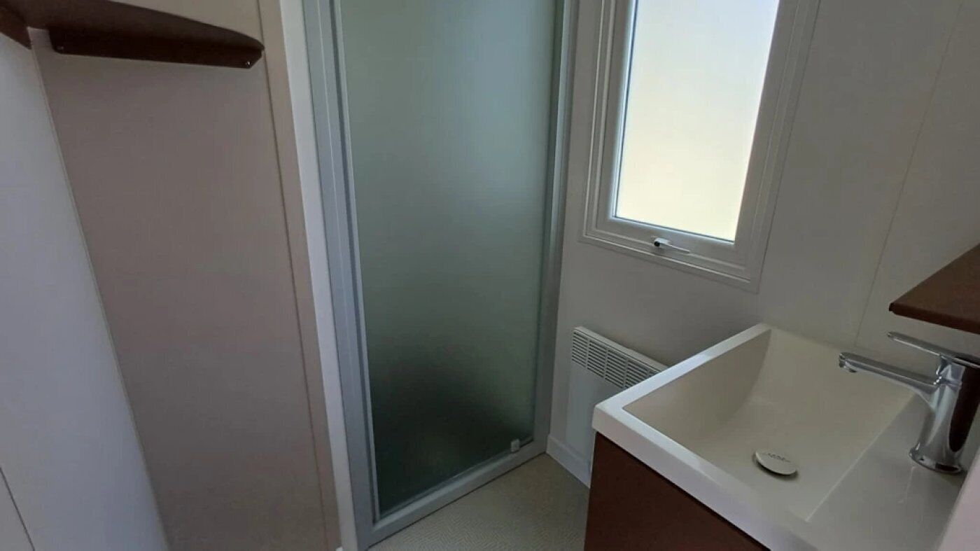 A bathroom with a shower, a window, and a sink.