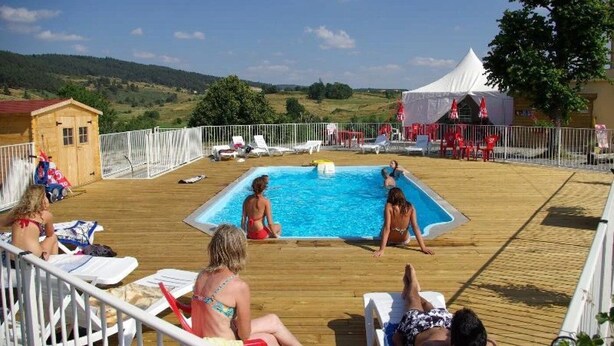 A pool area with a wooden deck, lounge chairs, and a small wooden building. - ZEcamping 3 étoiles piscine chauffée chiens acceptés mobil-home BBQ (Lesperon)